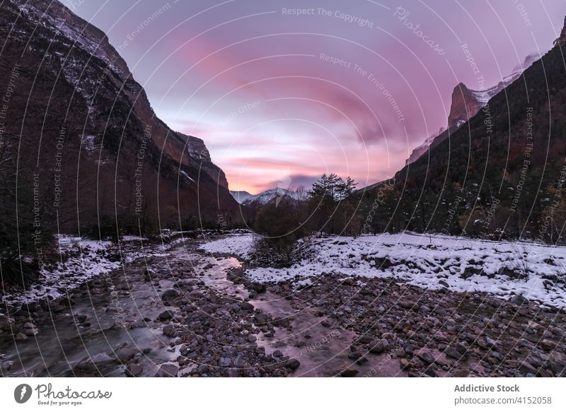 Fast river flowing through mountain valley forest landscape rocky wild stream terrain cloudy cold winter nature water splash stone rapid shallow peak scenic