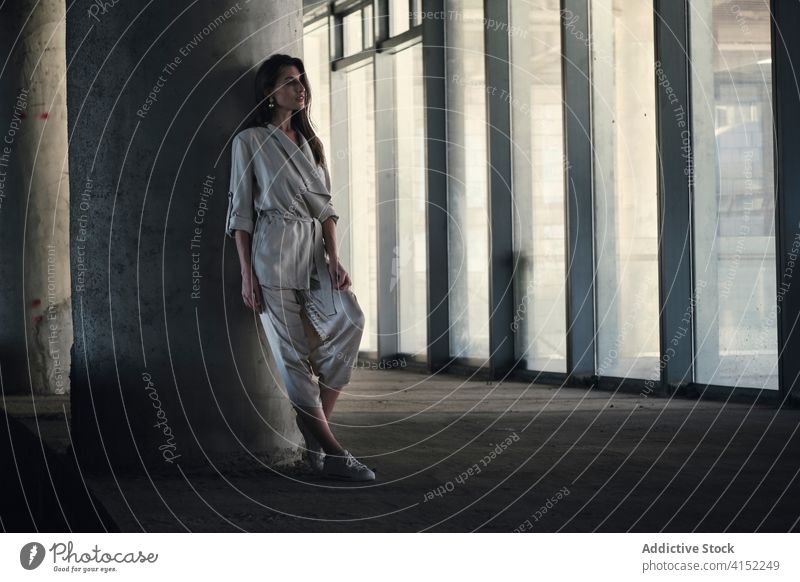 Young woman in stylish suit standing near concrete column style urban fashion pensive relax building thoughtful calm dreamy gray young female modern trendy