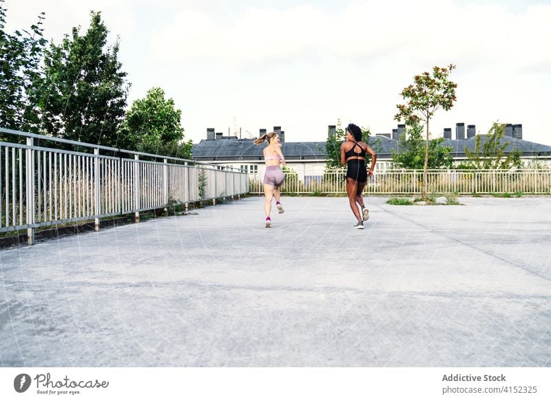 Fit diverse women running along concrete ground compete together training competition challenge sportswomen fast multiracial multiethnic black african american