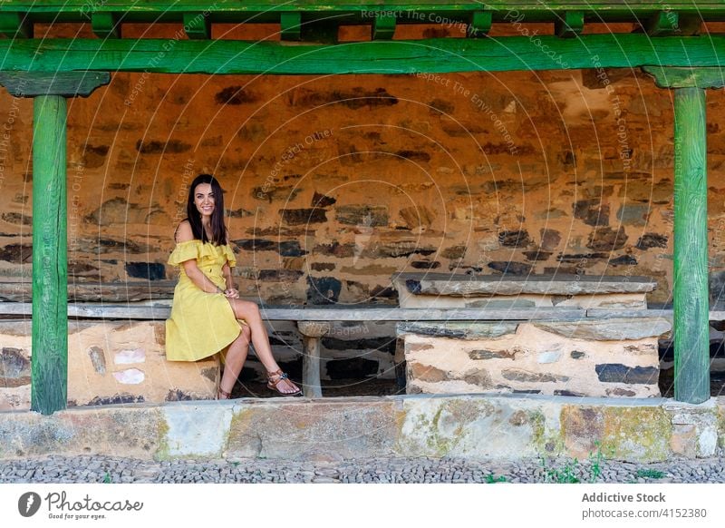 Smiling woman on shabby bench in city old town stroll weekend smile building weathered female summer dress relax rest street satisfied cheerful exterior happy