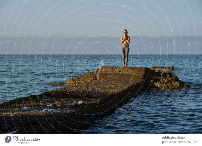 Serene woman in Mountain pose near sea mountain pose yoga meditate namaste rock asana calm harmony female tadasana relax tranquil wellness seascape summer