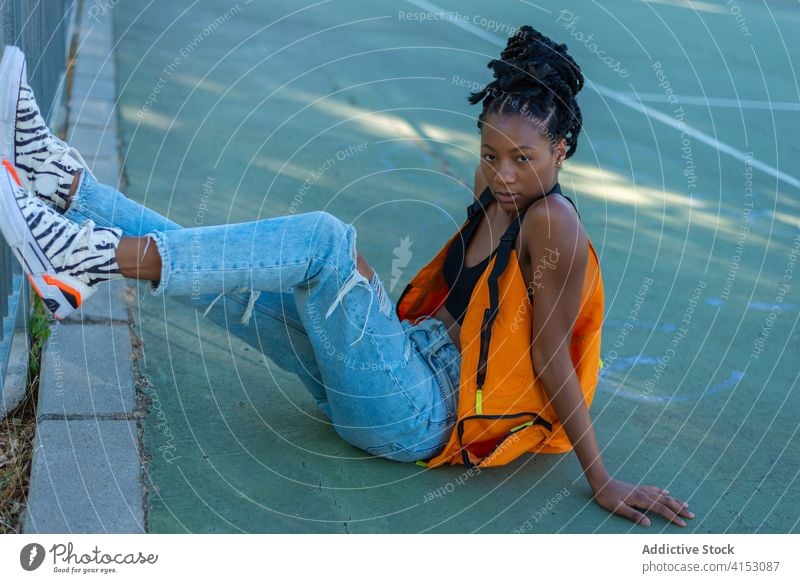 Fancy ethnic woman in stylish outfit sitting on floor in street fashion style trendy urban african american hipster young fancy black millennial female