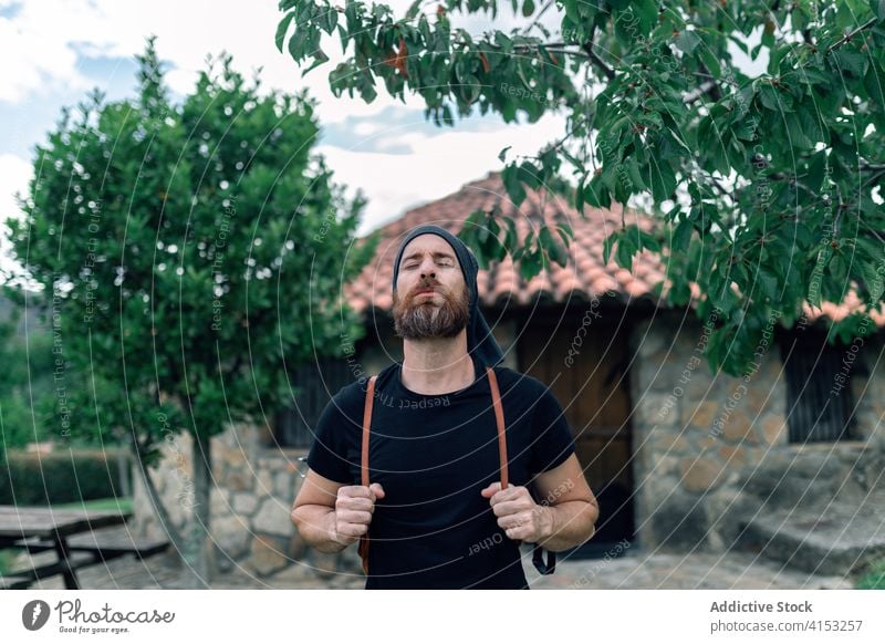 Traveling man with backpack in village traveler tourist settlement stone house wanderlust male adventure calm journey tourism serene admire scenic architecture