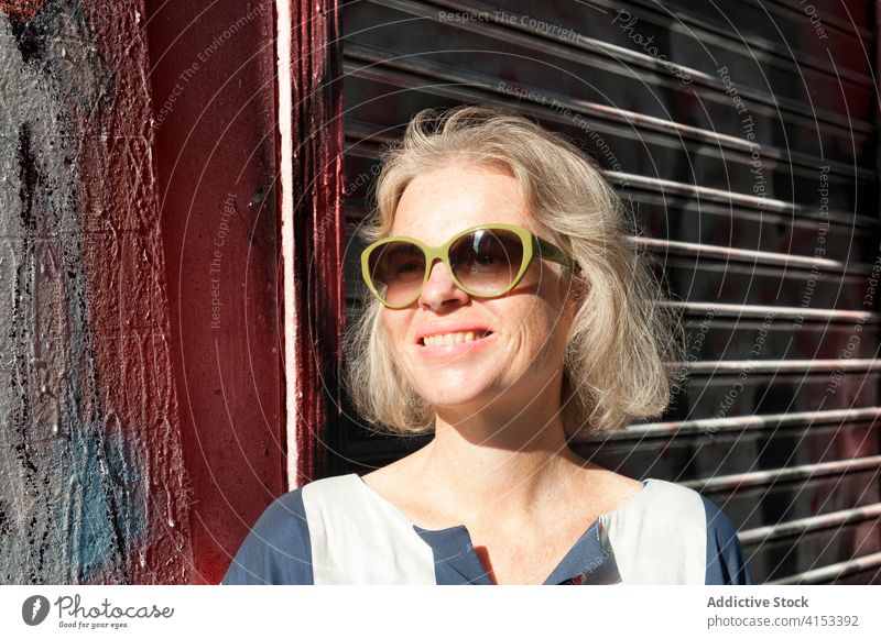 Stylish woman on city street graffiti wall trendy sunny weekend enjoy fashion female urban cheerful smile style happy relax delight summer chill lady satisfied