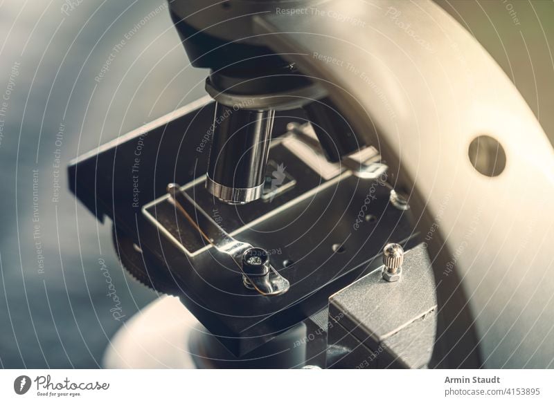 details of a silver microscope, with black background analyzing biology biotechnology brightly lit chemistry close-up closeup discovery education equipment