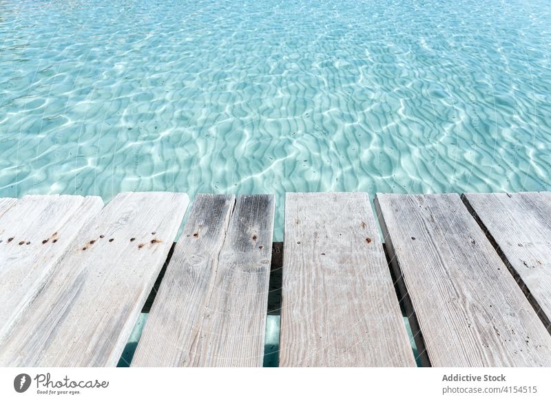 Wooden pier near sea on sunny day wooden clear flare water glare old quay playa de alcudia mallorca spain scenery nature scenic vacation summer coastline calm