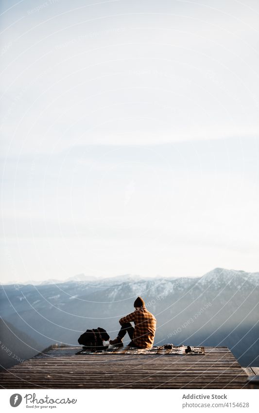 Traveling man sitting on hill and admiring view of mountains viewpoint traveler tourist landscape scenery ridge morning relax male germany austria nature