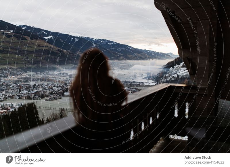 Woman on terrace admiring landscape of mountains travel hotel woman enjoy cityscape valley settlement winter female germany austria morning fog traveler wooden