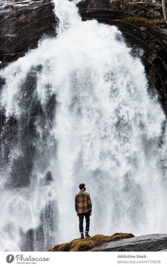 Traveling man near waterfall in mountains traveler winter highland hiker nature landscape stream male germany austria snow adventure hill trip journey tourism