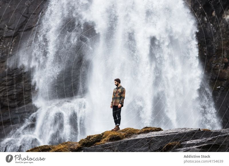 Traveling man near waterfall in mountains traveler winter highland hiker nature landscape stream male germany austria snow adventure hill trip journey tourism