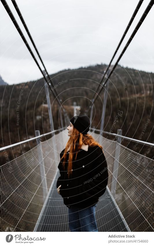 Traveling woman walking along bridge in mountainous area traveler highland wanderlust tourist suspension construction female germany austria vacation autumn