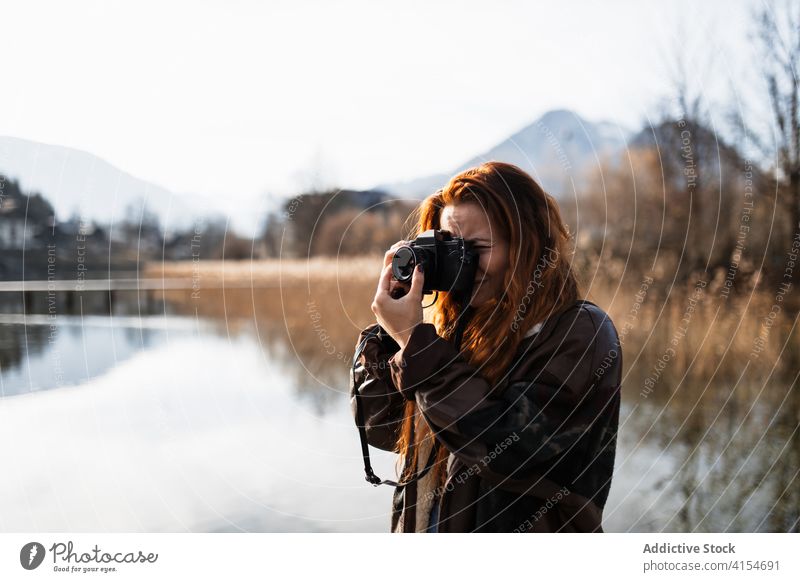 Photographer taking photos of nature near lake woman photo camera autumn photographer travel take photo shore shot mountain journey adventure young female