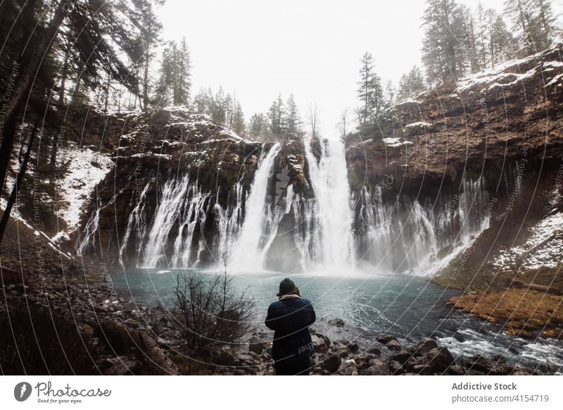 Anonymous person on waterfall in snowy mountainous forest in winter day flow nature landscape pool cold stream scenic picturesque scenery travel tourism usa