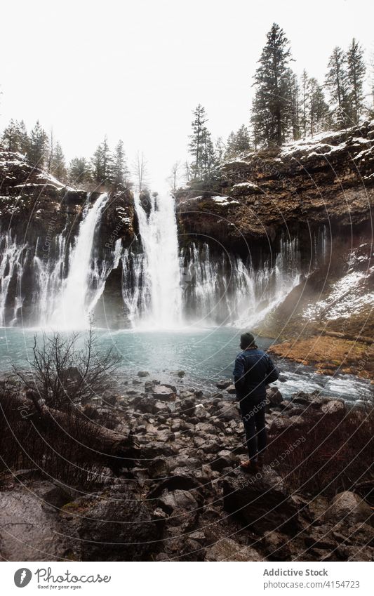 Anonymous person on waterfall in snowy mountainous forest in winter day flow nature landscape pool cold stream scenic picturesque scenery travel tourism usa