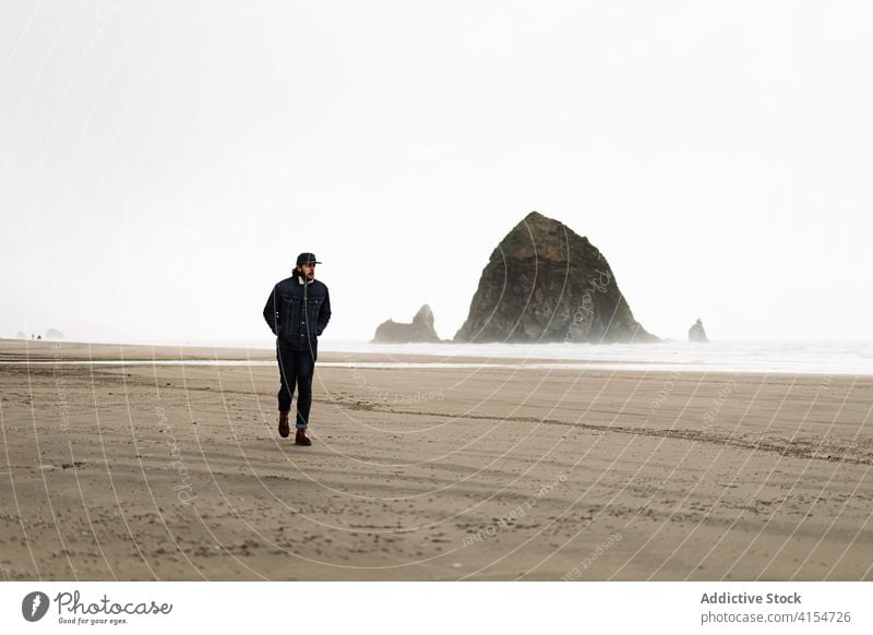 Male tourist at seaside on cloudy day man seashore walk seascape gloomy overcast foam nature usa united states america weather sky male ocean calm person