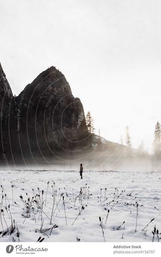 Anonymous person in peaceful view of mountains in winter blizzard valley highland snow cloudy nature rock landscape usa united states america scenic season