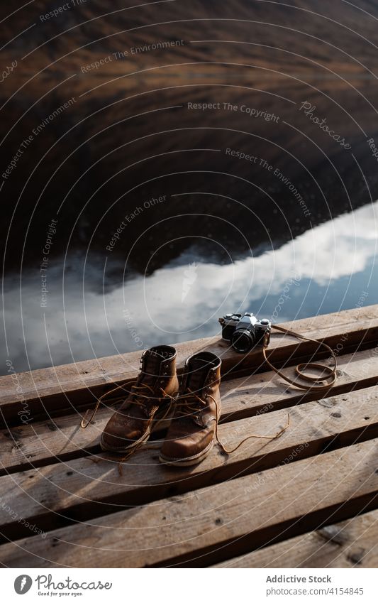 Trekking boots and vintage photo camera on pier trekking travel retro atmosphere footwear dirty scottish highlands scotland uk united kingdom shoe pair old