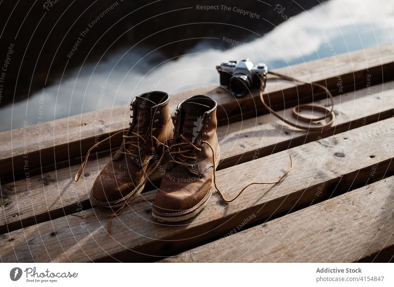 Trekking boots and vintage photo camera on pier trekking travel retro atmosphere footwear dirty scottish highlands scotland uk united kingdom shoe pair old