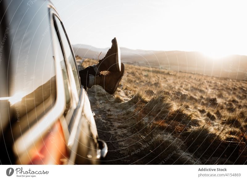 Crop traveler relaxing in car in mountains leg window sunrise highland journey road trip scottish highlands scotland uk united kingdom lying tourist vacation