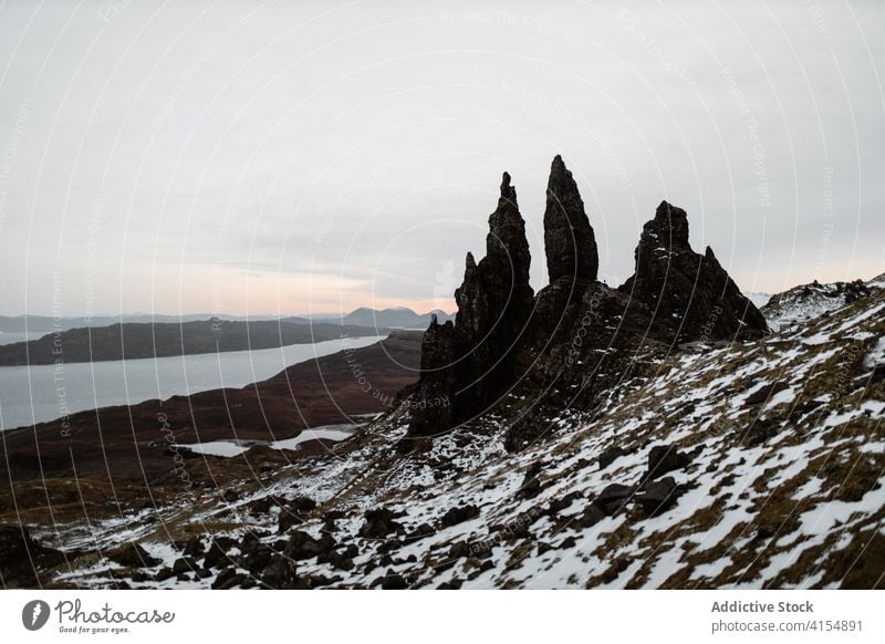 Rough rock on seashore in winter old man of storr snow slope rough formation landmark famous scottish highlands scotland uk united kingdom cloudy sky nature