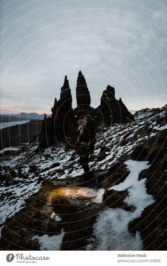 Traveling man near Old Man of Storr traveler winter old man of storr explorer season cold rock rough male scottish highlands scotland uk united kingdom slope