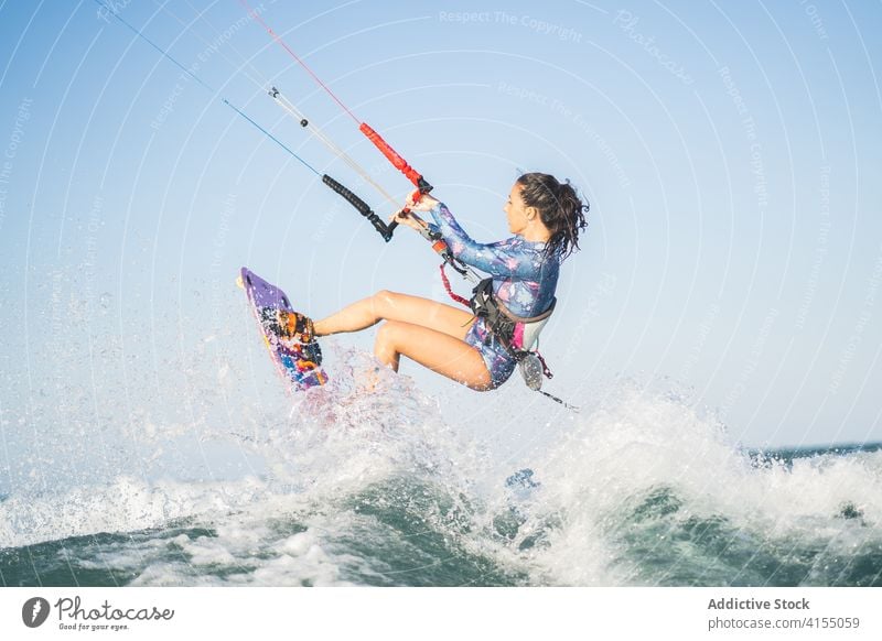 Female kite surfer riding on board in sea woman ride wave splash summer professional female swimsuit fit ocean recreation holiday swimwear surfing surfboard