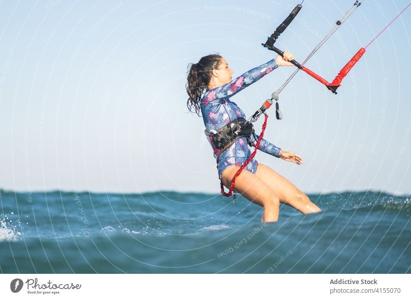 Female kite surfer riding on board in sea woman ride wave splash summer professional female swimsuit fit ocean recreation holiday swimwear surfing surfboard