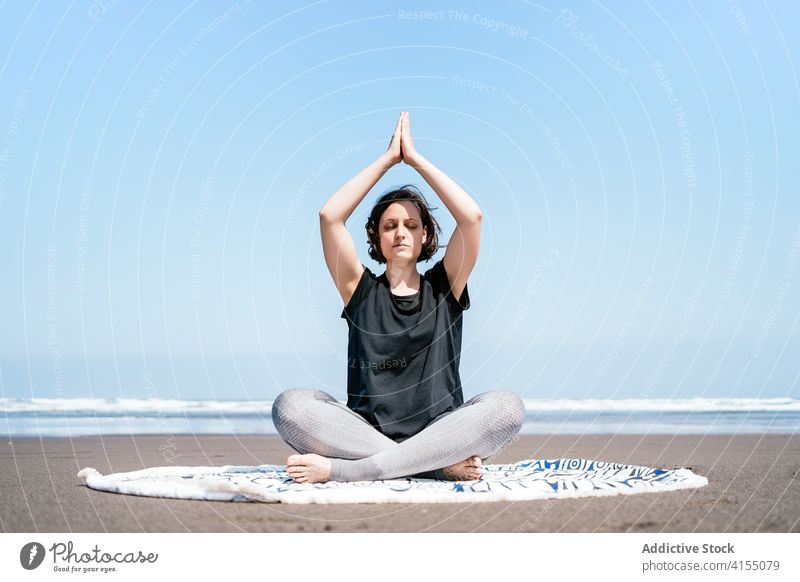 Slim woman doing meditation on beach yoga sea practice asana pose twist eyes closed sit balance calm seashore harmony wellness lifestyle flexible female nature