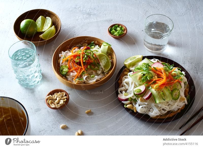 Vegan rice noodles salad food vegan top view cucumber vegetable lime peanut sauce asian cookery chinese fresh dinner green healthy bowl eating chopstick