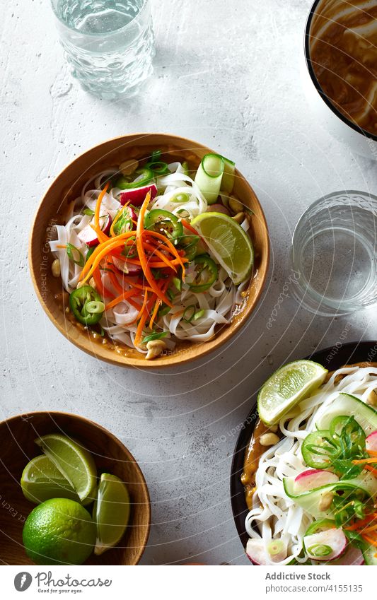 Vegan rice noodles salad food vegan top view cucumber vegetable lime peanut sauce asian cookery chinese fresh dinner green healthy bowl eating chopstick