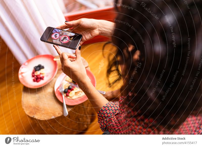 Woman using smartphone during breakfast pancake smile fresh tasty healthy fruit delicious raspberry mobile phone gadget honey happy organic photo food latin eat