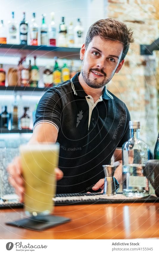 Crop barman preparing cocktail at counter nonalcoholic prepare bartender fruit kiwi garnish cold refreshment male glass slice drink beverage delicious serve