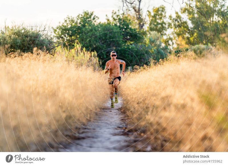 Energetic sportsman running on pathway in nature strong energy power athlete shirtless runner jogger workout endurance motion male lifestyle activity move