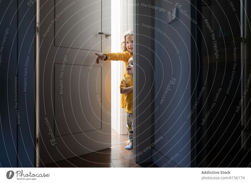 Cute siblings in doorway at home peep children playful brother sister having fun little apartment together cheerful modern cute adorable joy happy cozy smile