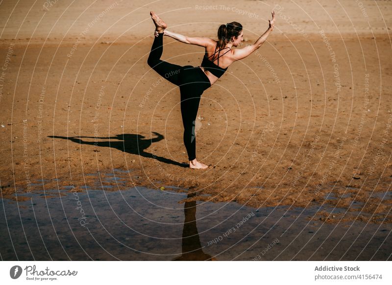 Anonymous woman doing yoga in Lord of the Dance pose lord of the dance pose natarajasana balance beach practice flexible river female shore fit calm nature