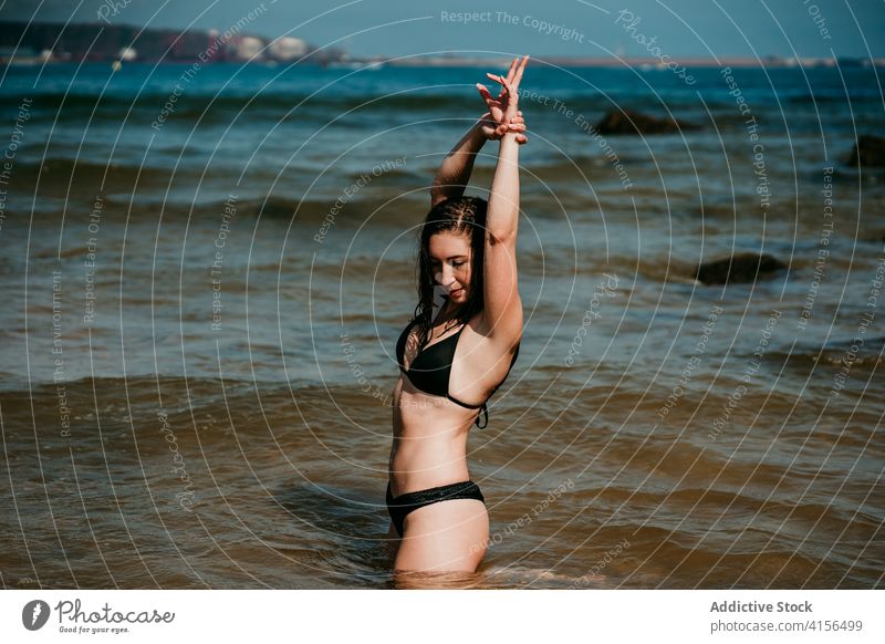 Tranquil woman in bikini at seaside enjoy vacation summer carefree cheerful seashore sunny female water clear resort nature rest freedom holiday calm sky happy