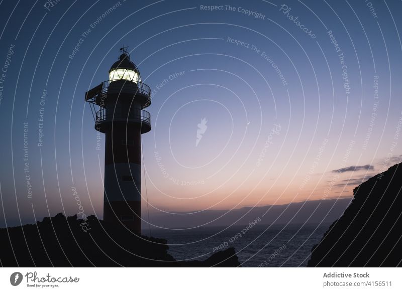 Lighthouse on cliff in evening lighthouse illuminate sea navigate guide beacon sunset spectacular tenerife sky canary island spain rocky hill breathtaking