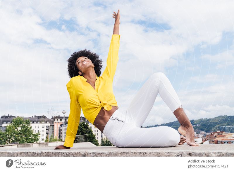 Optimistic black woman in trendy clothes smiling for camera and dancing with raised arms on sunny day in park dance smile style summer arm raised daytime fun