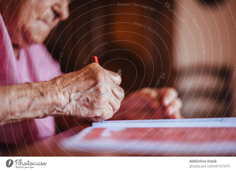 Older woman painting on a notebook old alzheimer mental health pencil retirement grandmother pensioner senior dementia female house elderly retired alone indoor