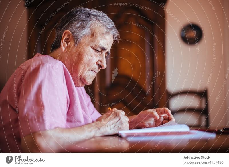 Older woman painting on a notebook old alzheimer mental health pencil retirement grandmother pensioner senior dementia female house elderly retired alone indoor