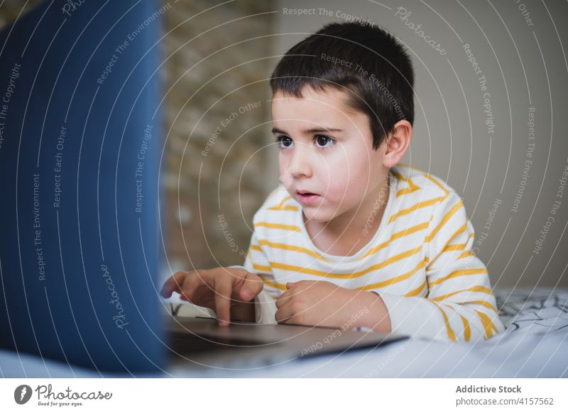 Little kid using laptop at home little gadget boy browsing bedroom child surfing internet addict device online lifestyle male preschool connection focus watch