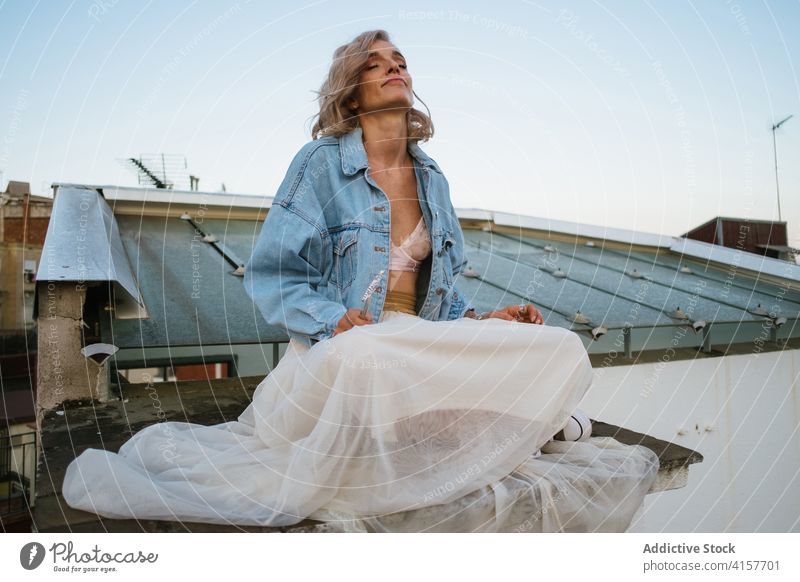 Carefree woman meditating on rooftop meditate yoga lotus pose namaste smile casual carefree asana female padmasana calm practice peaceful balance eyes closed