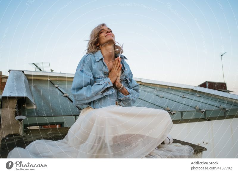 Carefree woman meditating on rooftop meditate yoga lotus pose namaste smile casual carefree asana female padmasana calm practice peaceful balance eyes closed