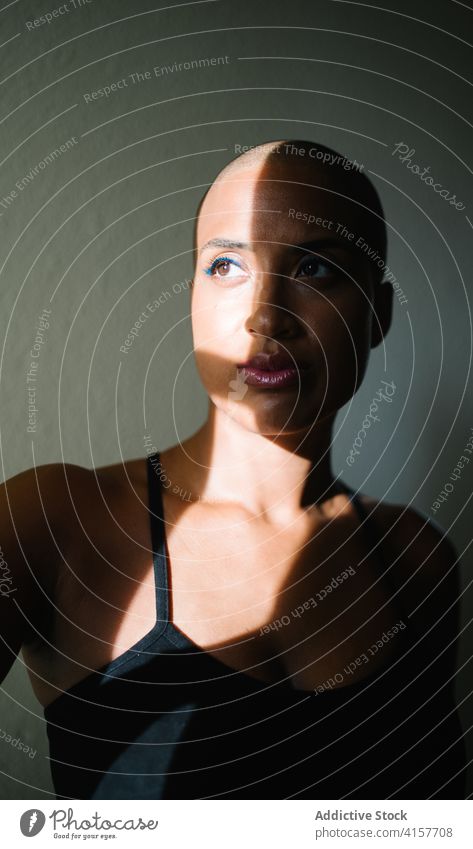 Serene black woman near window at home thoughtful sunbeam appearance contemplate apartment sunlight shadow relax female ethnic african american bald