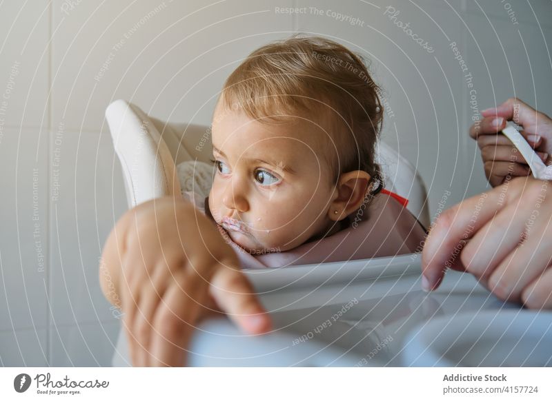 Toddler looking aside distractedly sitting on a high chair with a bib bonding innocence sharing infant motherhood togetherness wellbeing learn toddler