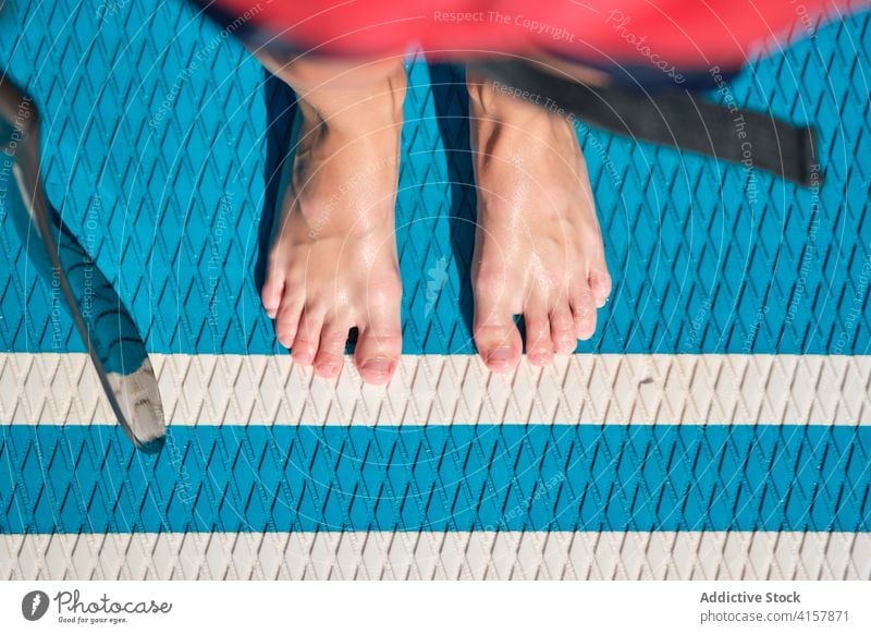 Feet of a kid on a paddle surfboard with a paddle lifestyles surfing stand teenager feet quiet fit recreation joy relaxation reflection standing calm vacations