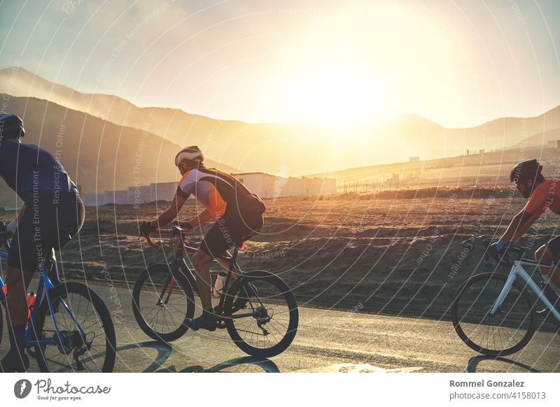 Group of cyclist friends riding race bike on sunset highway, sunset bike competition. group cycling professional training fitness sport lifestyle biker