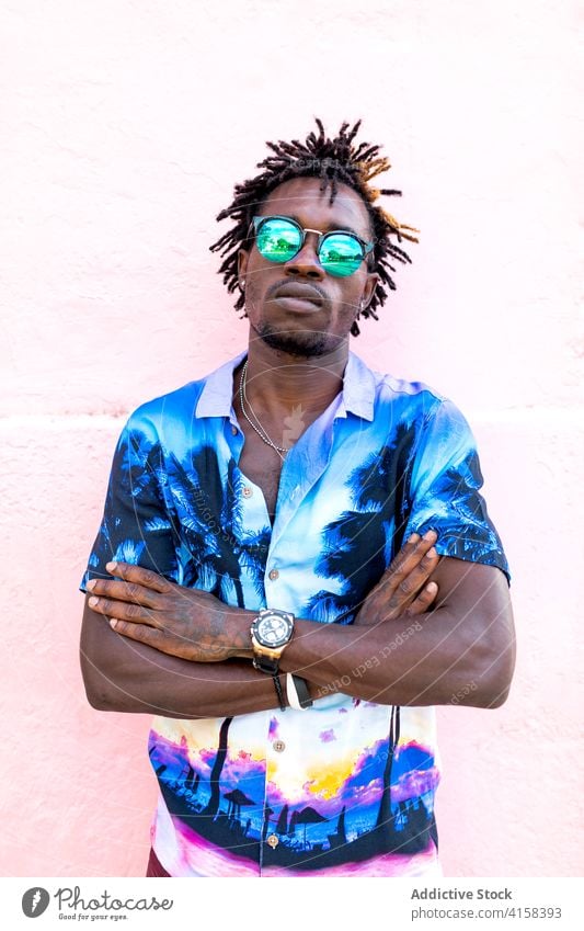 Stylish black man in sunglasses in city shirt palm tree print trendy style confident determine handsome male ethnic african american street building wall