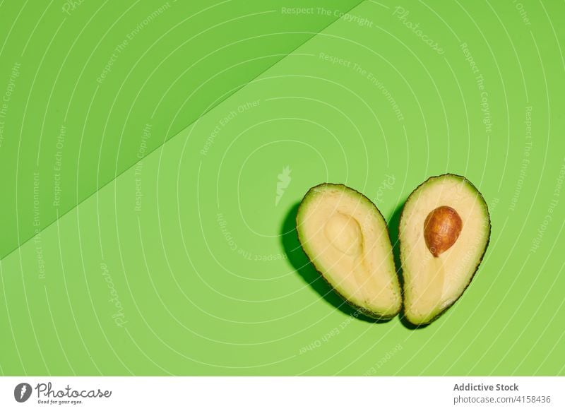 Halves of fresh avocado on green background half fruit slice cut piece seed ripe tropical exotic color colorful bright vivid vibrant organic delicious vitamin