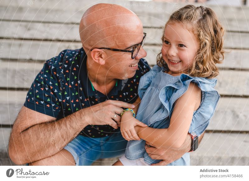 Cheerful father and daughter in city fatherhood embrace stroll together kid relationship hug adorable little girl joy bonding glad relax weekend urban cute love